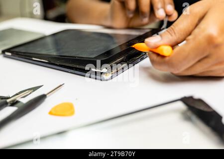 A skilled technician meticulously removes a tab's display using specialized tools Stock Photo