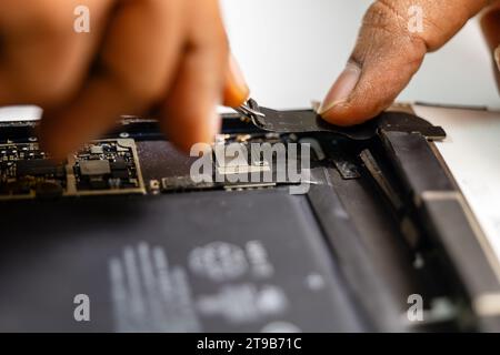technician carefully removes the damaged ribbon from a tablet using specialized tools Stock Photo