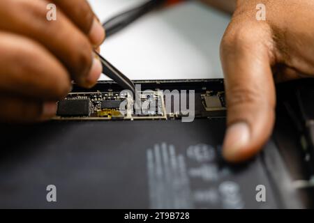 An image of a focused technician meticulously repairing a tablet Stock Photo