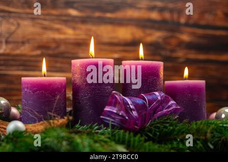 Augsburg, Bavaria, Germany - November 24, 2023: Christmas wreath with four burning purple candles for Advent *** Weihnachtskranz mit vier brennenden lila Kerzen zur Adventszeit Stock Photo