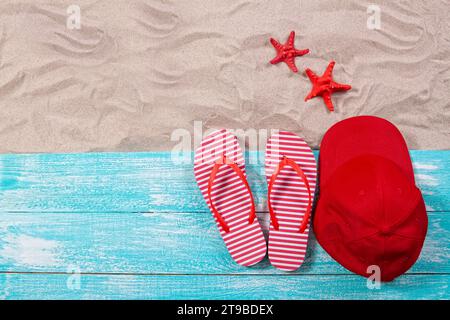 Starfishes, flip flops and a cap on a blue board on the sand copy space - summer concept Stock Photo