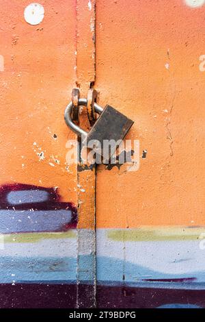 A padlock secures the metal doors of a colofully painted utility closet on a Tel Aviv street. Stock Photo