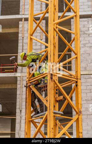 The two construction workers are on a crane in a construction site Stock Photo