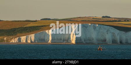 Fishing boat in front of Seaford Head Nature Reserve and chalk cliffs of Seven Sisters, East Sussex, England Stock Photo
