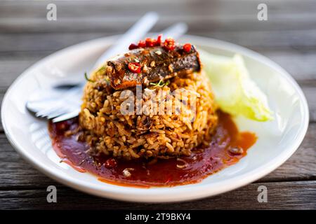 Fried Rice with Canned Mackerel in white dish on a wooden table. Thai style fusion food. Stock Photo