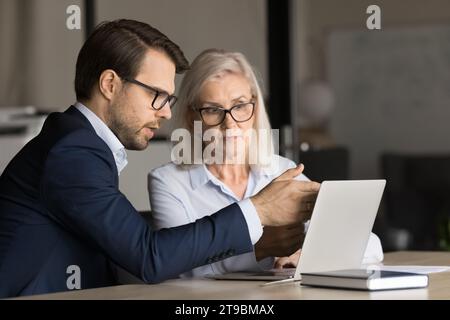 Two serious business colleagues collaborating on Internet project at laptop Stock Photo