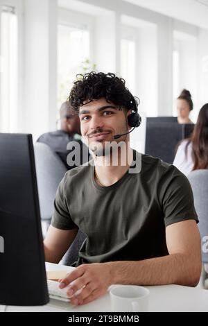 Man wearing headset using desktop PC in office Stock Photo