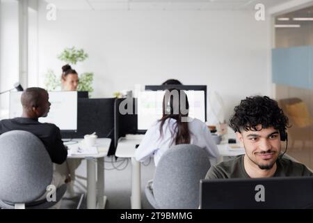 Man wearing headset using desktop PC in office Stock Photo