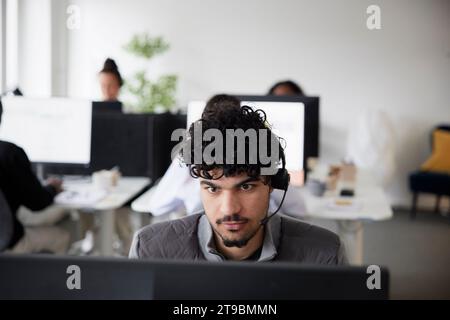 Man wearing headset using desktop PC in office Stock Photo