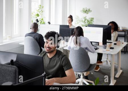 Man wearing headset using desktop PC in office Stock Photo
