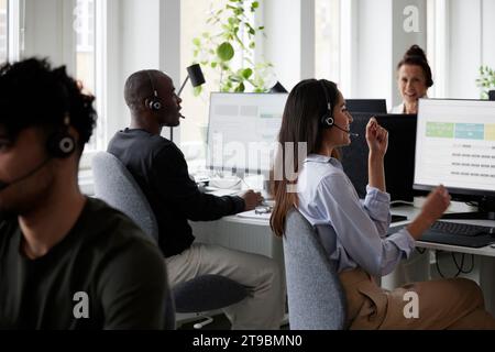 People working in call center office in front of desktop PCs Stock Photo