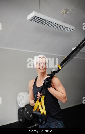 Smiling senior woman standing in gym and looking at camera Stock Photo