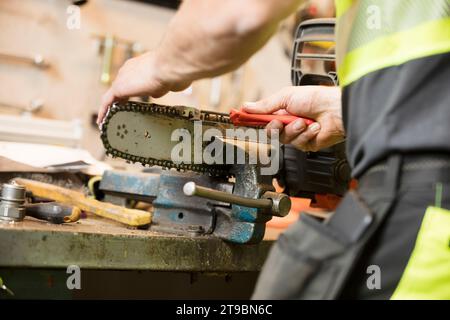 Man working on chainsaw in workshop Stock Photo