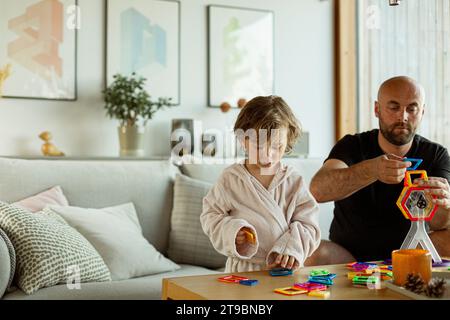 Father and son playing together in living room Stock Photo