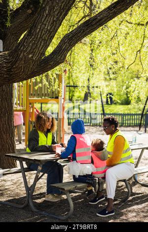 Female friends with their children spending leisure time in park Stock Photo