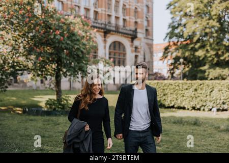 Female and male colleagues talking while walking together in city Stock Photo