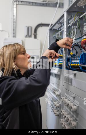 Female technician checking cables in control room at industry Stock Photo