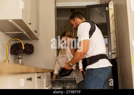 Parents helping each other while working in kitchen at home Stock Photo