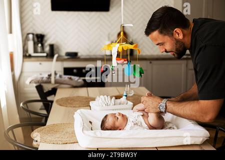 Father changing diaper of son lying down on table at home Stock Photo