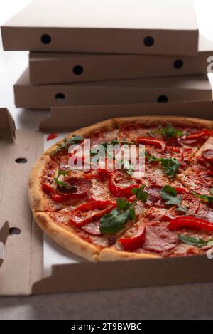 Large Pizza in open carton box on kitchen table closeup view Stock Photo