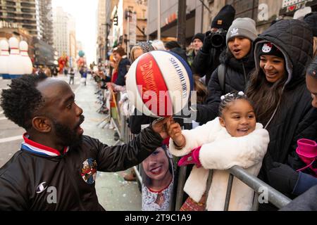 Brenda Bauchman, 4 laughs as Hot Shot Swanson from the Harlem Globetrotters places a spinning basketball on her thumb as her family watches, during the Macys Thanksgiving Day Parade on Thursday November 23, in Manhattan, New York. (Photo by Mattie Neretin/Sipa USA). Credit: Sipa USA/Alamy Live News Stock Photo