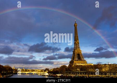 The Eiffel Tower stands gracefully to the right, framed by the Seine River as a magnificent rainbow arcs across the golden hour sky. Paris, France Stock Photo