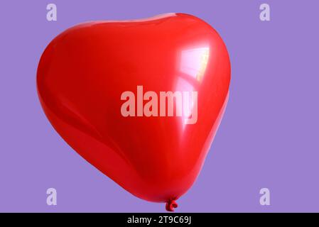 Red heart shaped balloon on violet background Stock Photo