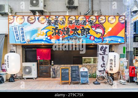 Modern style Japanese izakaya restaurant. Large name board over the entrance, various menu boards outside with large white chochin, lantern. Stock Photo