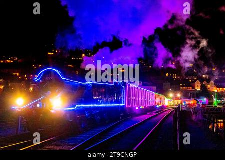 Kingswear, Devon, UK.  24th November 2023.   The Christmas Train of Lights on the Dartmouth Steam Railway which runs between 24th November to 30th December 2023, pulls out of Kingswear station in Devon on its way to Paignton.  The carriages and steam locomotives on the festive service are lit inside and out with coloured lights.  Picture Credit: Graham Hunt/Alamy Live News Stock Photo