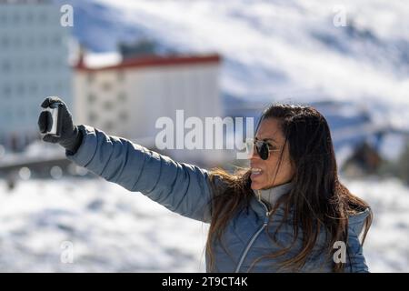 Young man taking a selfie in the mountains of sierra nevada, in the ski resort of granada., Stock Photo