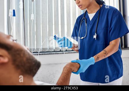 focus on african american nurse setting drop counter next to her blurred indian male patient Stock Photo