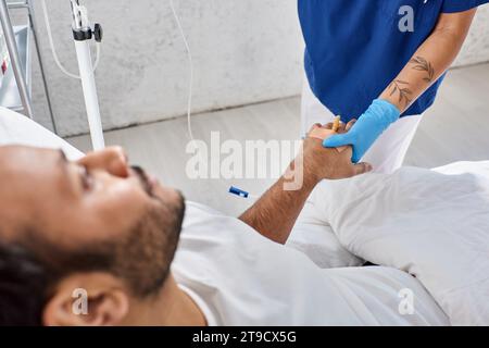 focus on african american nurse setting drop counter next to her blurred indian patient, cropped Stock Photo