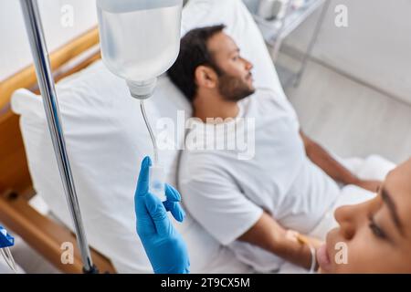 focus on african american nurse setting drop counter next to her blurred indian male patient Stock Photo