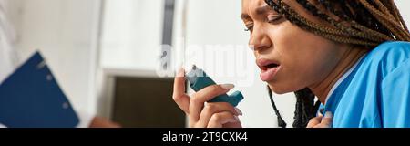 focus on ill african american patient using her inhaler next to her blurred indian doctor, banner Stock Photo