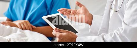 cropped view of african american woman in hospital bed next to indian doctor holding tablet, banner Stock Photo
