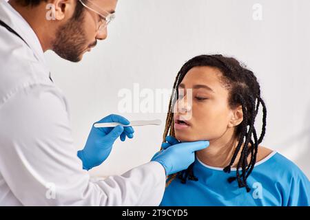 young ill african american woman in hospital ward having doctor check up of throat, healthcare Stock Photo