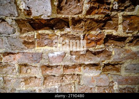 Close-up outdoor view of part of an ancient stone wall with a textured surface. An abstract image of a brown cemented, durable facade Stock Photo