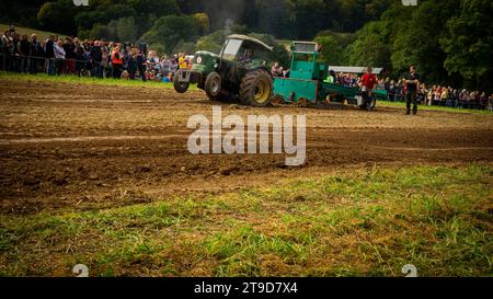 Spectators Gather for Vintage Tractor Showdown: Rustic Charm Meets Strength in Grassland Pulling Contest Stock Photo
