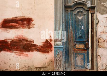 Shabby wooden door in an old building with cracked walls Stock Photo