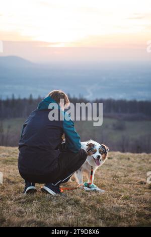 Young cynologist, a dog trainer trains a four-legged pet Australian Shepherd in basic commands using treats. Love between dog and human. Stock Photo