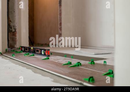 Tile levelling system, four plastic green clips with wedges. Close-up view, selective focus, blurred background. Stock Photo