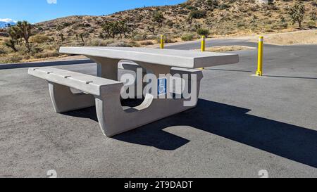 ADA Wheelchair accessible cement picnic table in a parking area of a desert recreation area Stock Photo