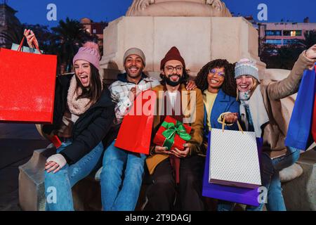 Group of best friends celebrating the christmas together, showing their shopping bags. Happy people with xmas gifts and presents enjoying a festive night. Buddies purchasing sales at christmastime. High quality photo Stock Photo