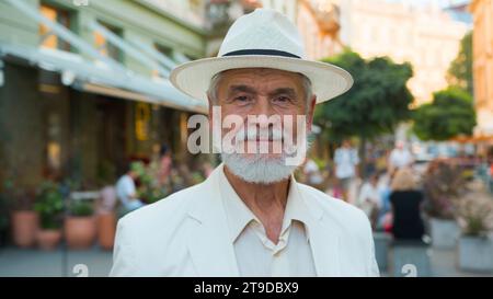 Close up calm old senior 60s elderly mature gray-haired Caucasian elegant man retired businessman intelligent male tourist looking camera outside city Stock Photo