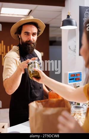 Storekeeper at zero waste supermarket checkout counter using bar code ...