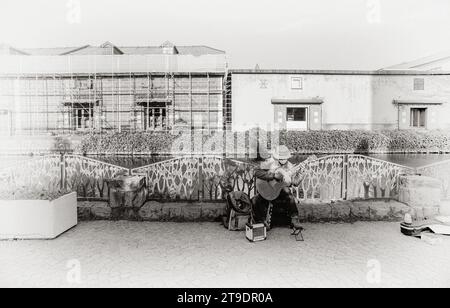 Street performer plays guitar at Otaru canals and warehouse in Hokkaido Japan. Text in Japanese is "Otaru storehouse". Stock Photo