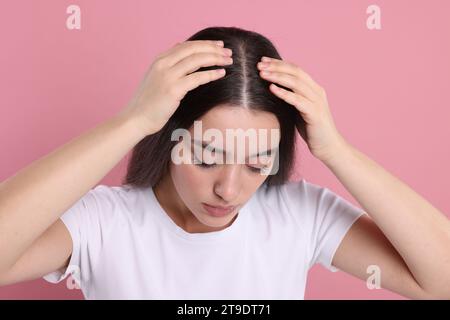 Woman examining her hair and scalp on pink background Stock Photo