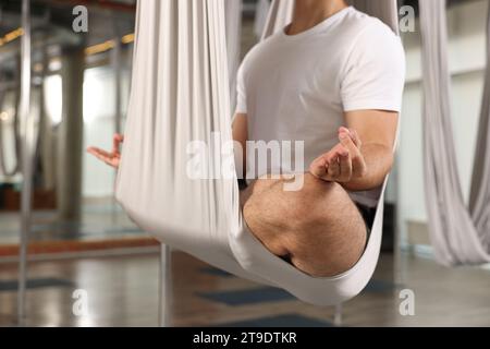 Man meditating in fly yoga hammock indoors, closeup Stock Photo