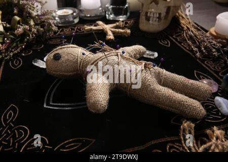 Voodoo doll with pins and dried flowers on table Stock Photo