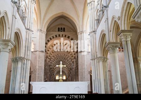 Vezelay, FRANCE - JULY 20, 2023: Inside Basilica of Saint Mary Magdalene at altar with golden cross framed by nave arches. Stock Photo